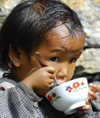 Nepal - Langtang region - young child eating rice in a bowl - photo by E.Petitalot