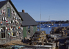 Maine, USA: lobster traps and floats on fishing wharf  wooden house with shingles - photo by C.Lovell